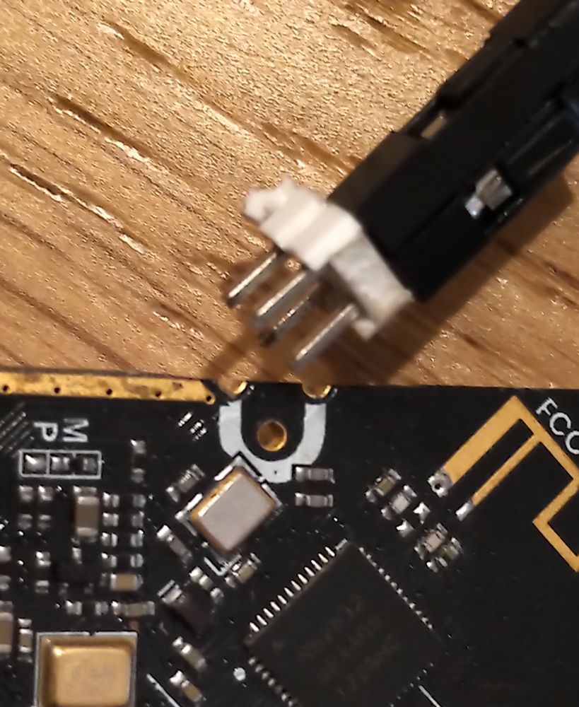 a 2x2 2.54" pin header with jumpers, lined up next to some holes in a micro:bit V2 PCB