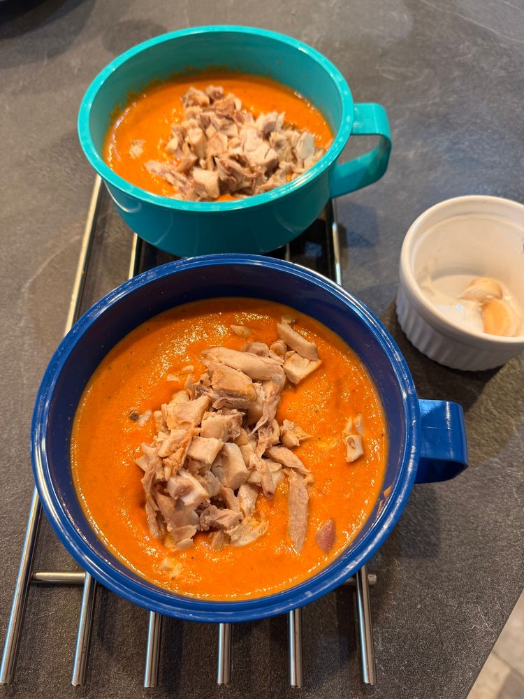 Two bowls of tomato chilli soup with diced chicken thigh.