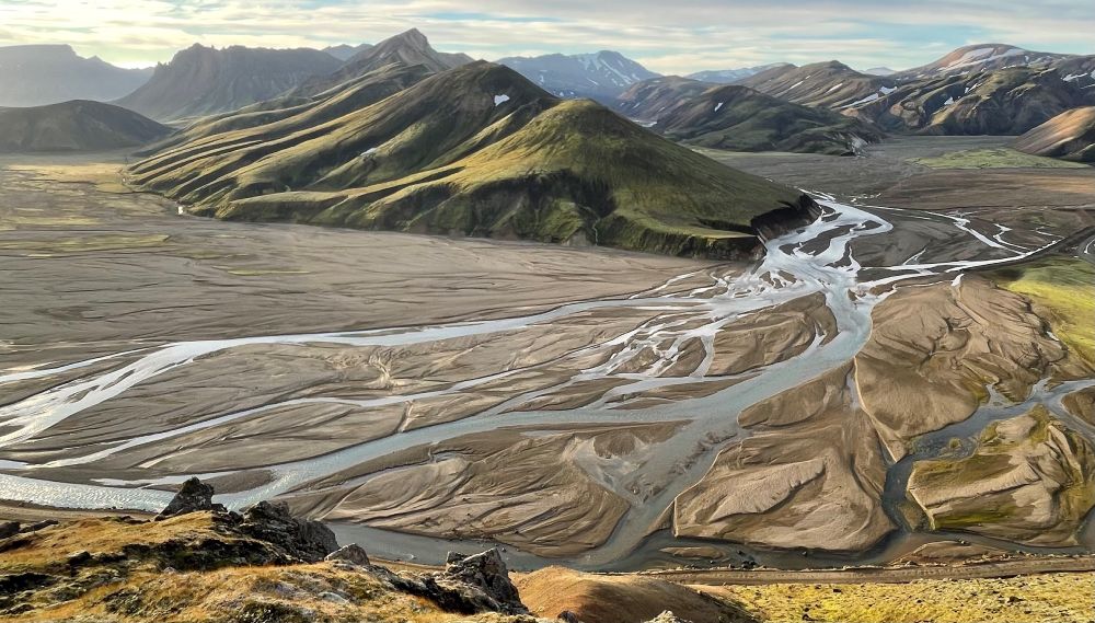 Photo showing a braided river with mountains in the background 