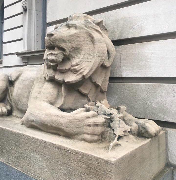 statue of a lion pawing at what appears to be leaves in a bowl, so it looks like a salad to me 