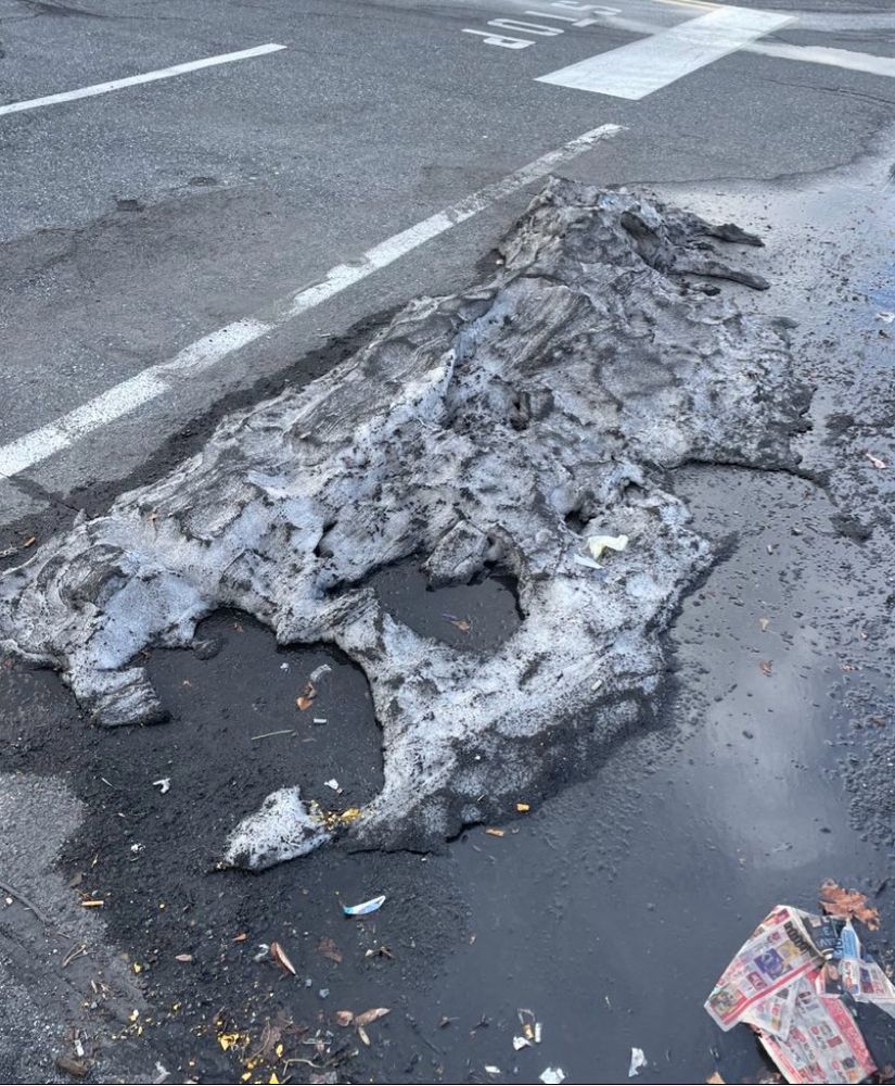 a pile of half-melted snow in a dirty parking lot - that is shaped exactly like the illustration of the mountainous green island surrounded by blue water, with a nice little lake in the middle  
