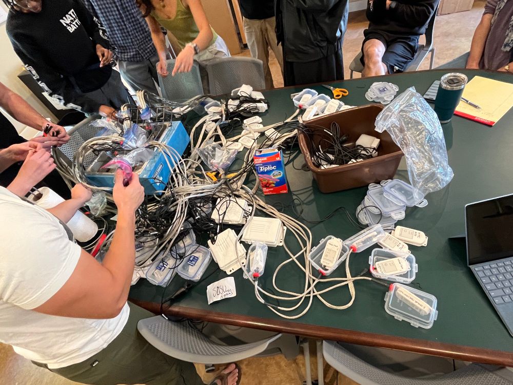 Figuring out our thermometer calibration set up (college students and professors work together at a round table)