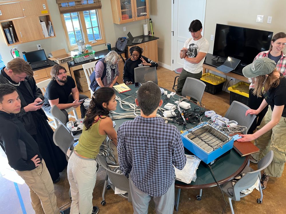 Figuring out our thermometer calibration set up (college students and professors work together at a round table)