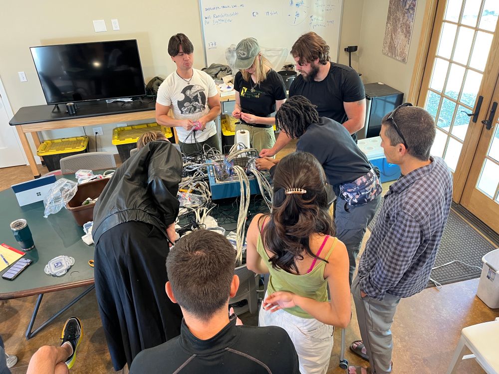 Figuring out our thermometer calibration set up (college students and professors work together at a round table)