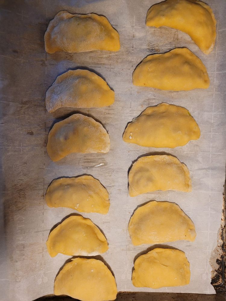 Color photographic image of two vertical rows of six pierogi each, pre-boiling. 