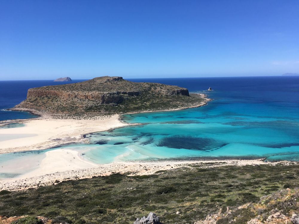 Beautiful landscape looking down from a hill you can see incredible turquoise sea and a little island in the middle of the photo