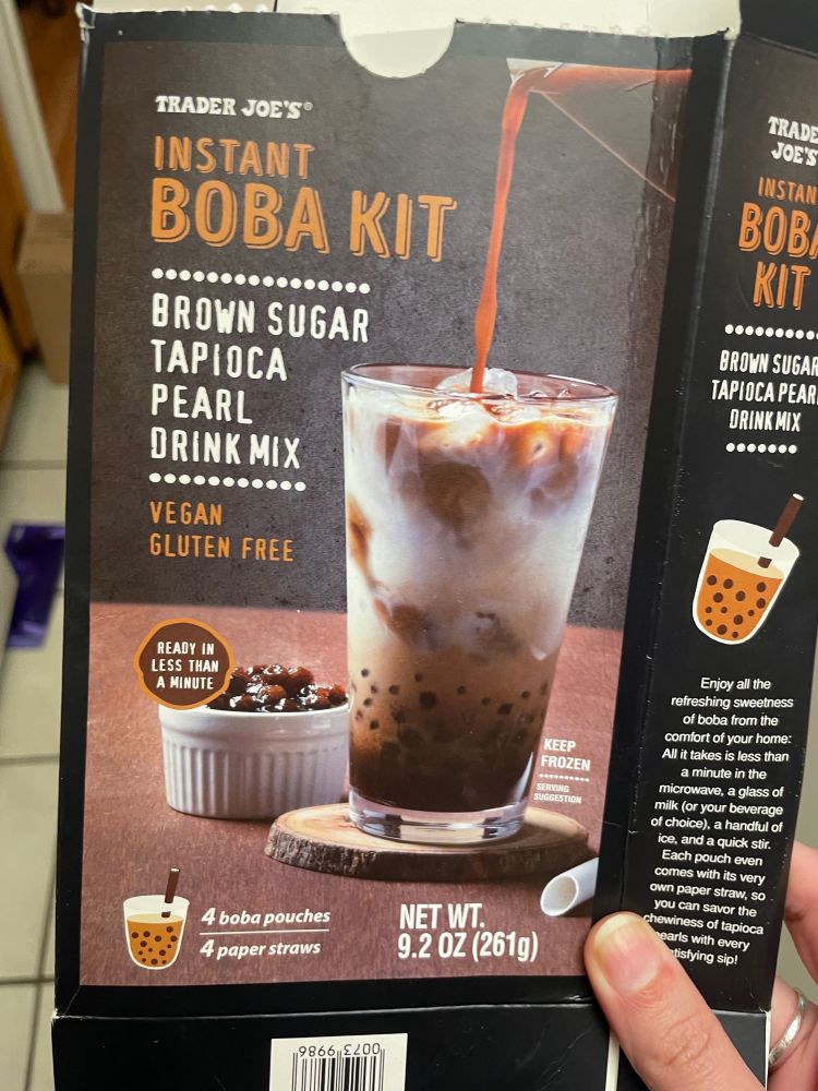 Trader Joe’s Instant Boba Kit packaging. It reads “Trader Joes Instant Boba Kit, Brown sugar tapioca pearl drink mix. Vegan gluten free. Ready in less than a minute” and shows a glass of boba tea with ice with tea being poured into the glass.