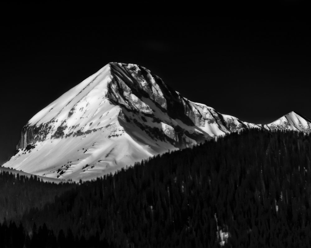 Black and white image of a snow-loaded mountain.
