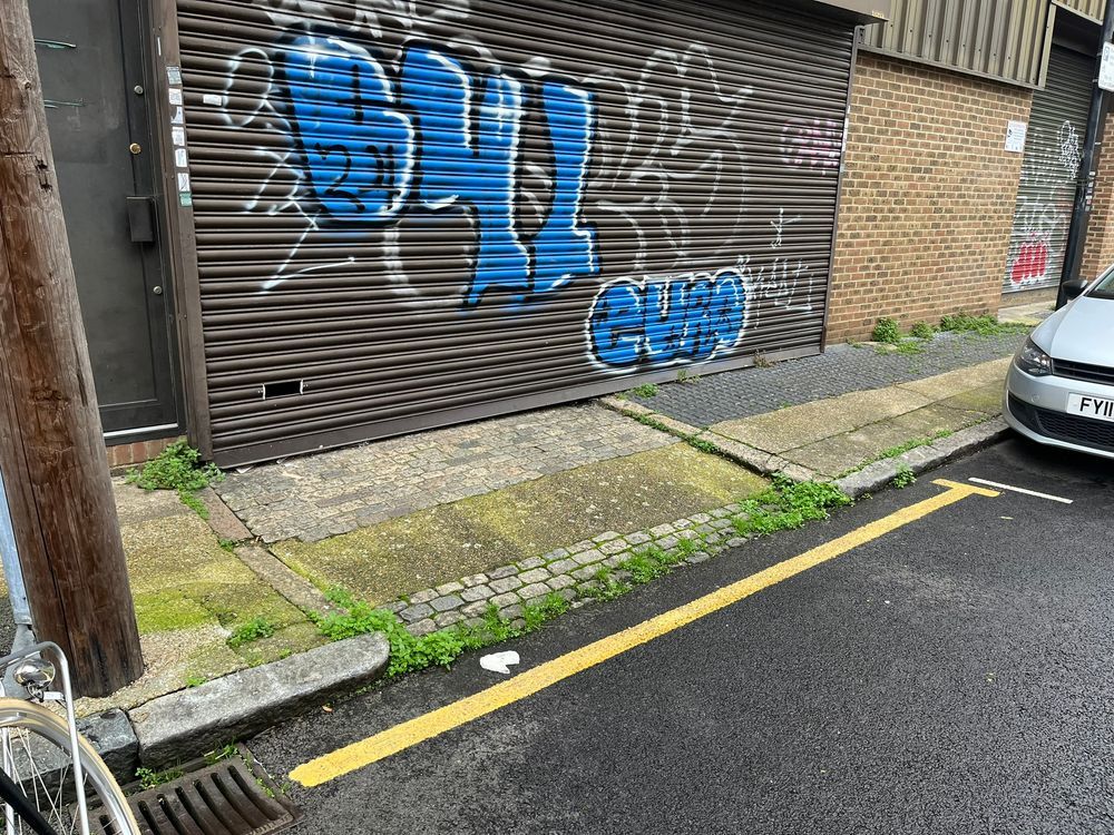 The pavement is interrupted by an entrance way. On one side of the entrance way, the dropped kerb is not flush with the road surface