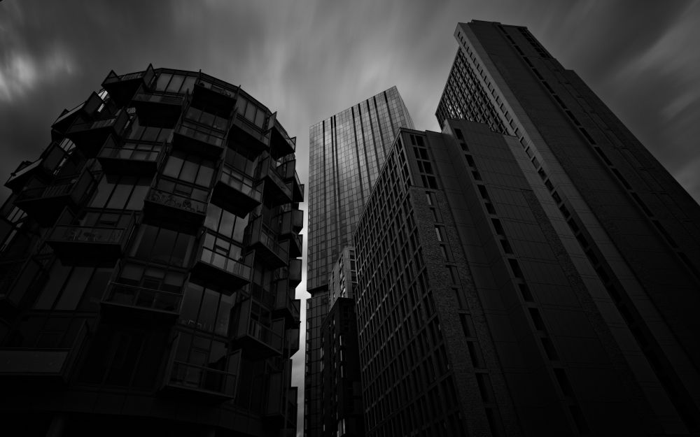 3 condensed buildings against a moody skyline in black and white