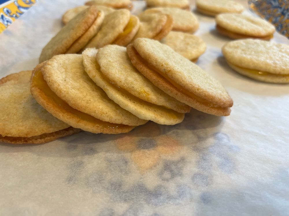 A small pile of pale yellow sandwich cookies. 