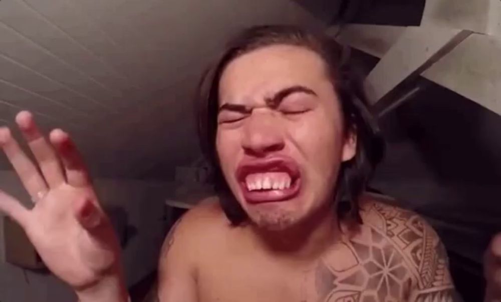 a shirtless man with a tattoo on his arm is making a funny face with his mouth open .