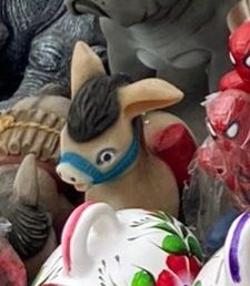 Cute little brown ceramic donkey surrounded by other ceramic items 