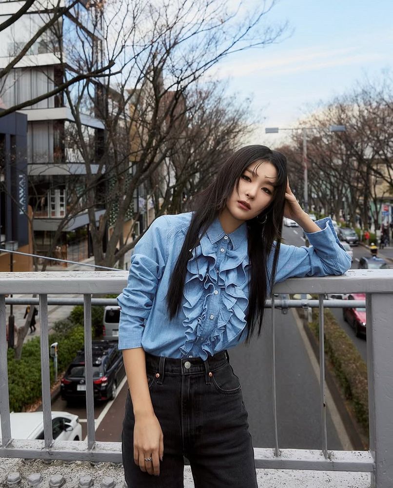 Seulgi for Levi’s Korea. Blue button up denim top with ruffles along the buttons and dark wash jeans. Her hair is long black and straight. 