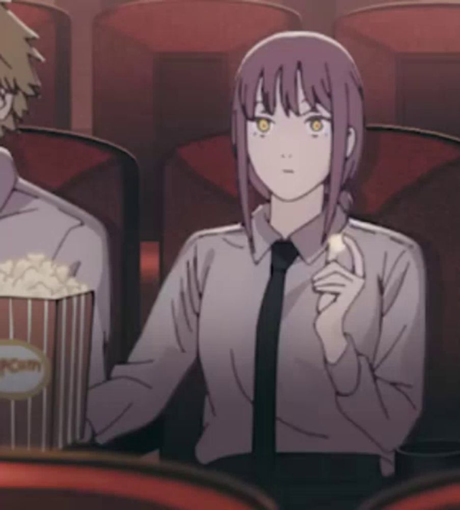 a man and a woman are sitting in a theater eating popcorn and watching a movie .