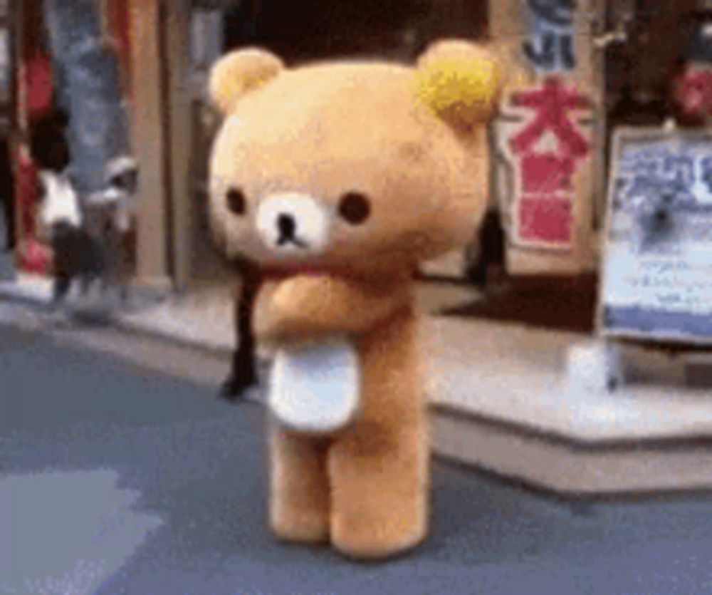 a teddy bear is standing on a street in front of a store .