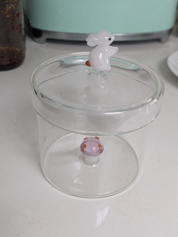 Glass jar with white bunny on top and mushroom on the bottom
