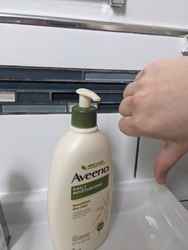 An Aveeno lotion pump that faces mostly out with a thumbs down next to it
