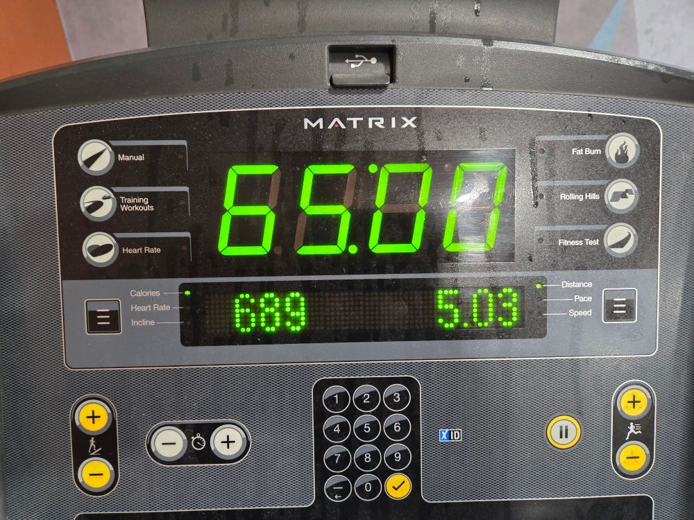 Treadmill screen showing I ran 5.03 miles in 65 minutes, burning 689 calories in the process