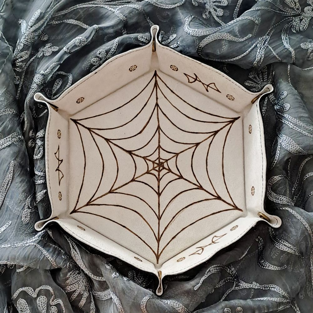 Bandeja de cuero interior color blanco con una telaraña y motivos abstractos pirograbados. 