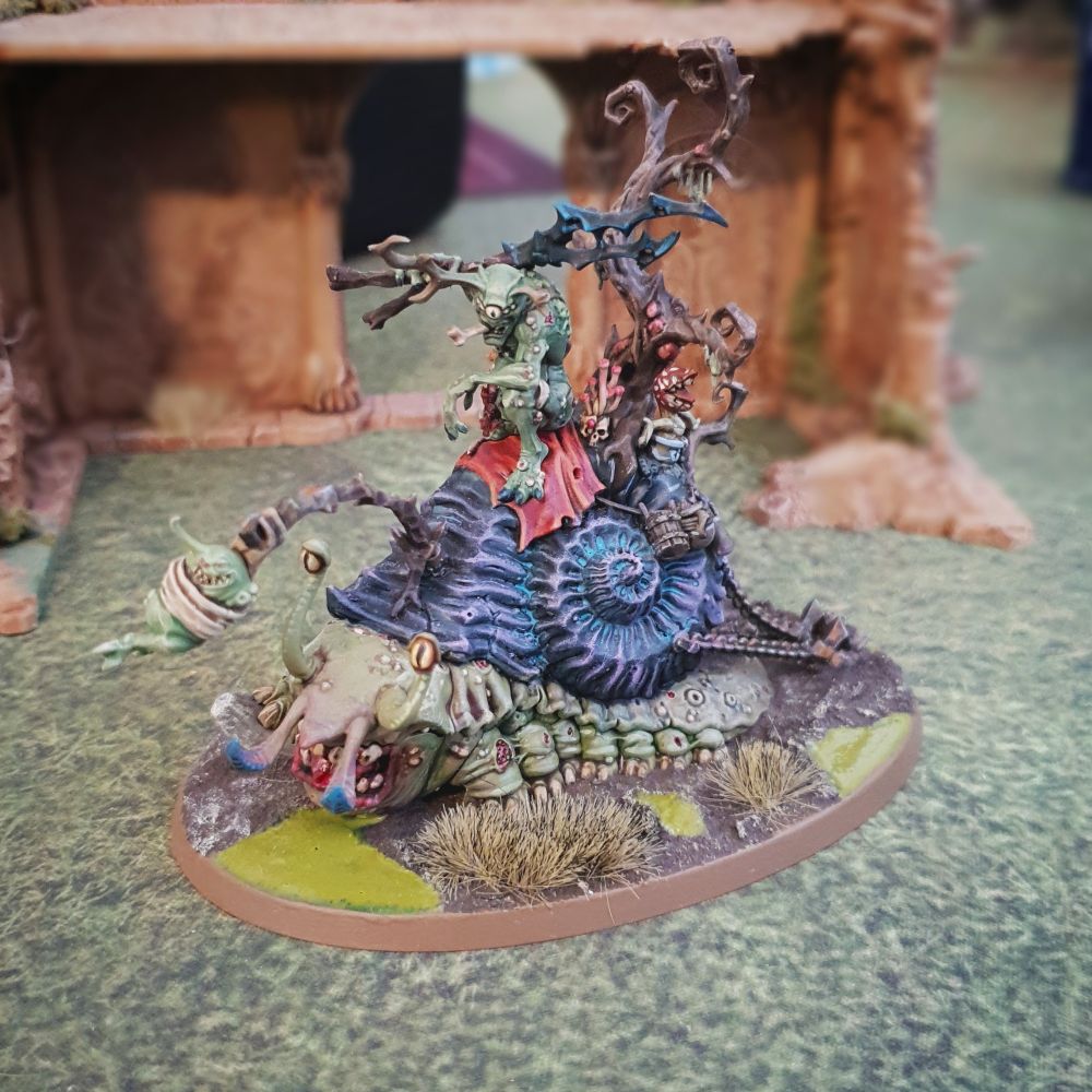 A Nurgle plague demon rides on a giant snail 