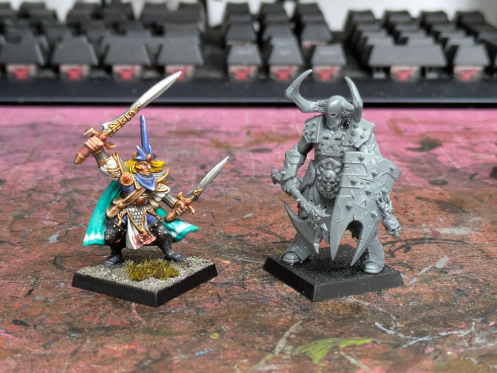 A High Elf ranger with two swords faces a huge chaos warrior with axe and shield