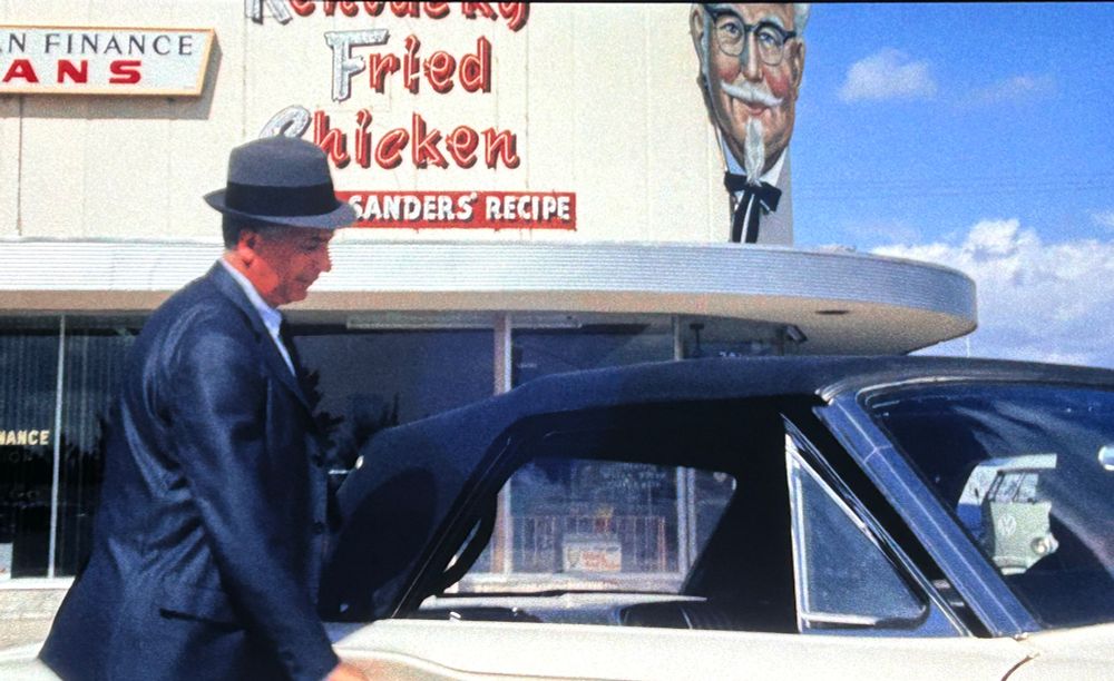 a big lighted sign that says Kentucky Fried Chicken Sander’s Recipe next to the colonel’s head.