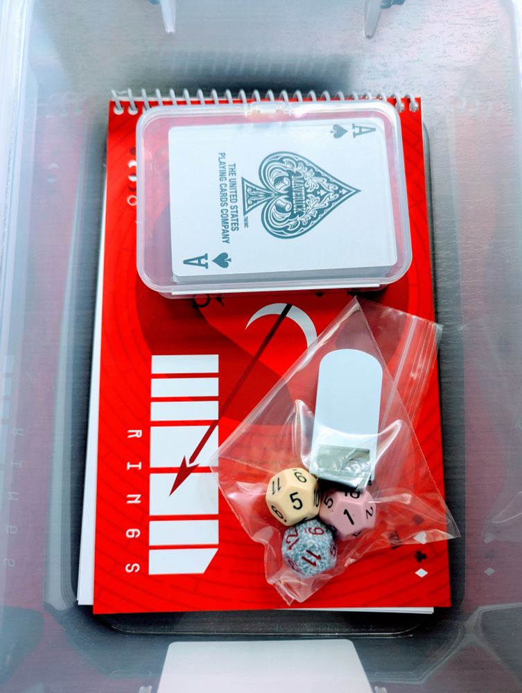 The game Moon Rings in a plastic bin with cards, dice, and a character standee