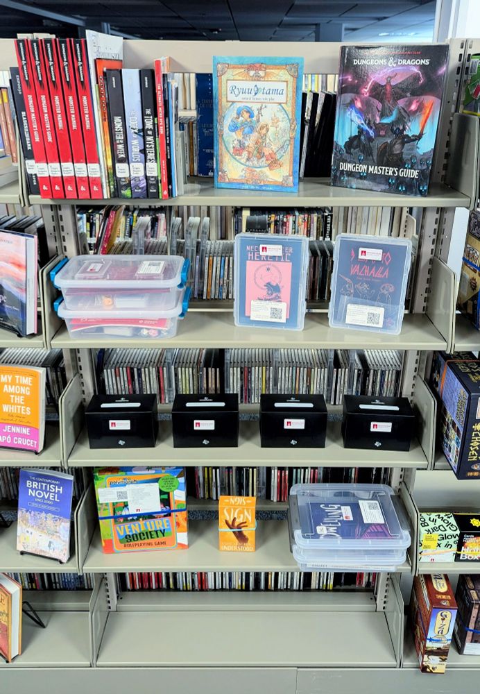 A bookshelf in an academic library. The top four shelves are filled with TTRPGs. The bottom shelf is empty 