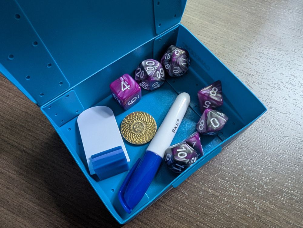 Inside the Gamegenic "Token Holder" case there is: 1 RPG dice set, 1 coin, 1 dry erase marker, and 1 plastic character standee