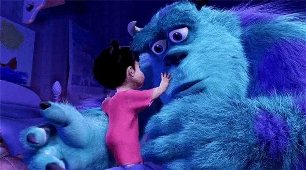 a little girl is touching the face of a blue monster from monsters inc .