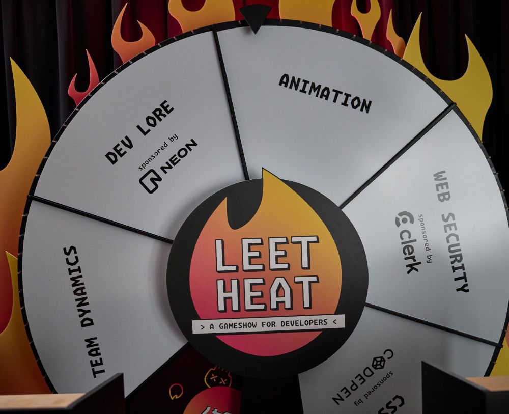 a game show wheel with web development categories. There is a "dev lore" category sponsored by Neon, a "Web Security" category sponsored by Clerk, a "CSS" category sponsored by CodePen, and two unsponsored categories: "Team Dynamics" and "Animation". the center of the wheel has the "Leet Heat" logo. there are flame cutouts around the wheel