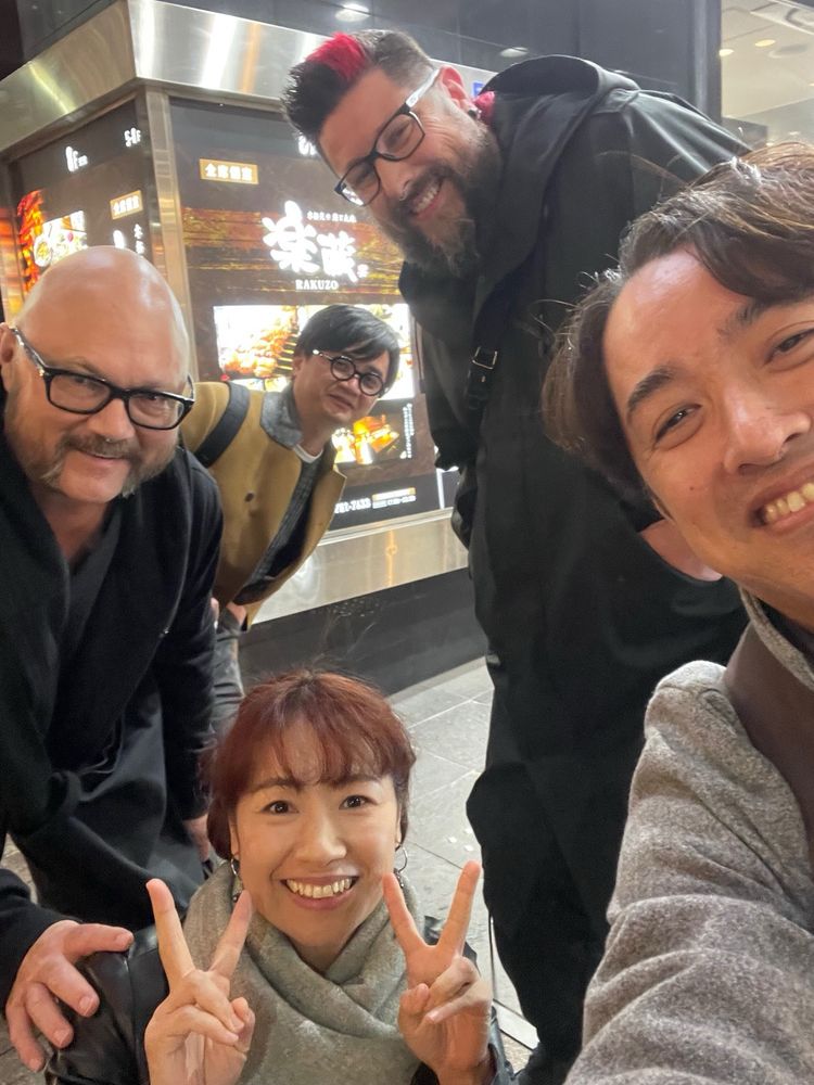 Photo of Hiroyuki Nakamuru holding the camera and in the lower right, his wife is in the bottom of the frame, Robert Takahashi Novak is left or frame, Soloi Sound in the center back and I am looming in the upper right corner. We are all smiling and Mayumi is making peace sings with both hands.