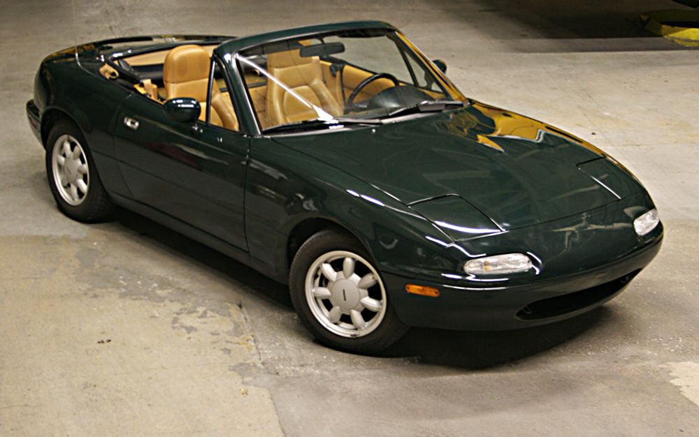 A 1991 British Racing Green special edition, parked in a garage with its top down.  