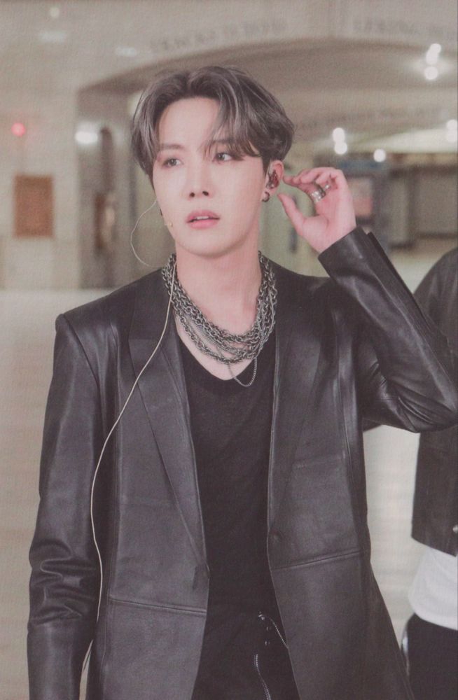 Hobi in a black jacket and lots of necklaces
