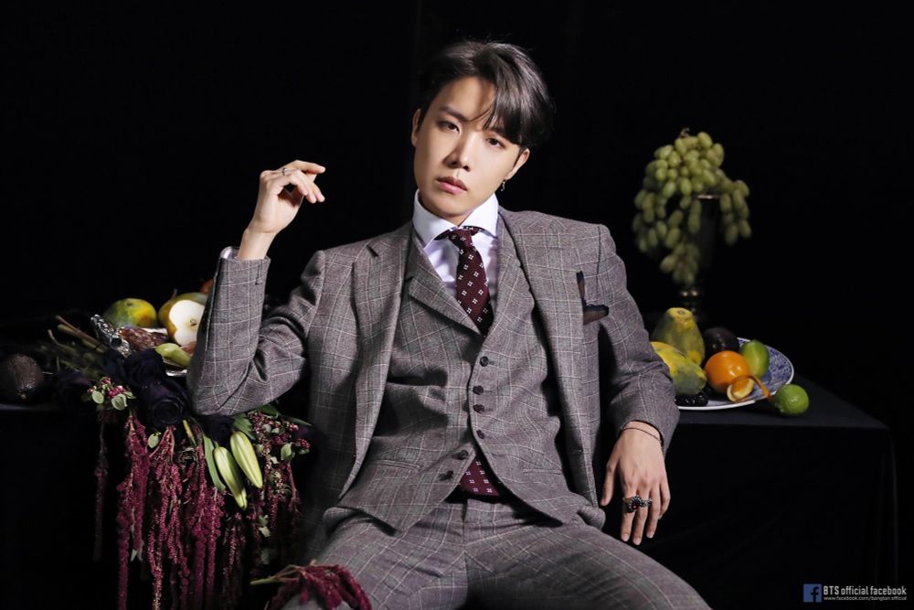 Hobi in a grey suit looking like he's judging all your choices. 