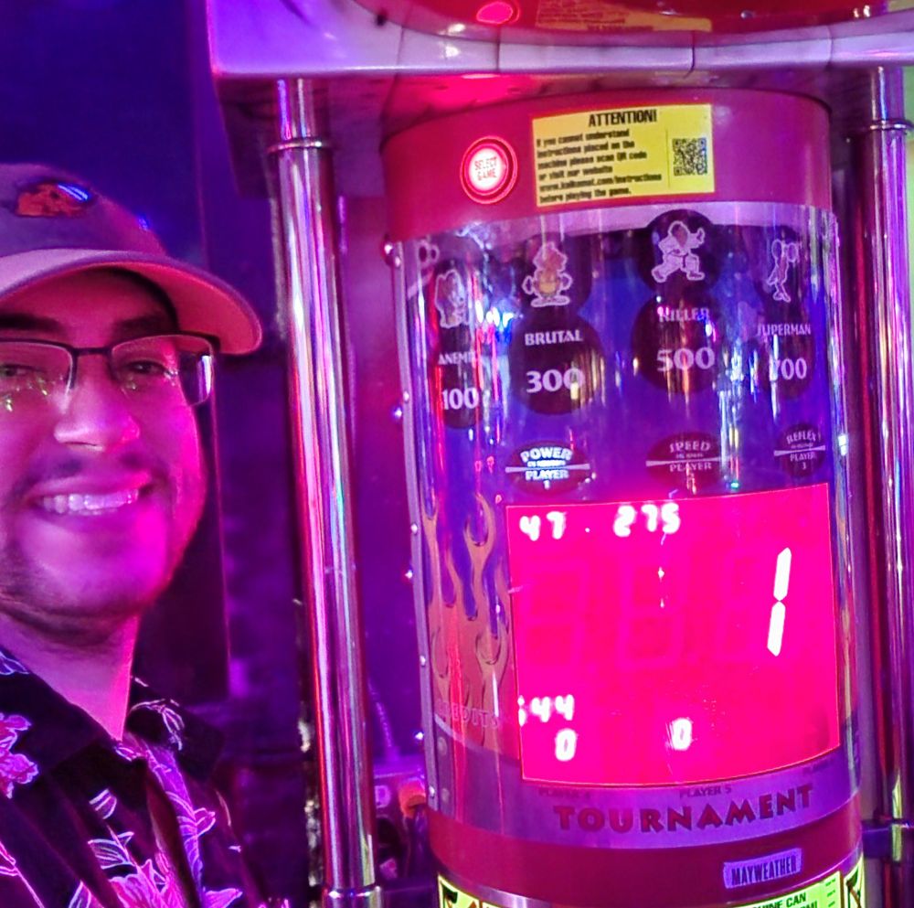 Epic gamer stands in front of punch machine with new high (low) score of "1".