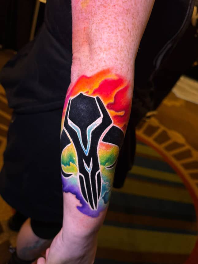 A new-style mythosaur skull tattoo with a bunch of rainbow watercolor behind it. 