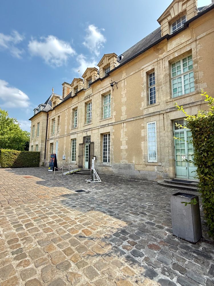 Vue de l’entrée du château d’Auvers-sur-Oise, l’entrée est assez simple, il y a le rez-de-chaussée et un premier niveau et une grande cour pavee 