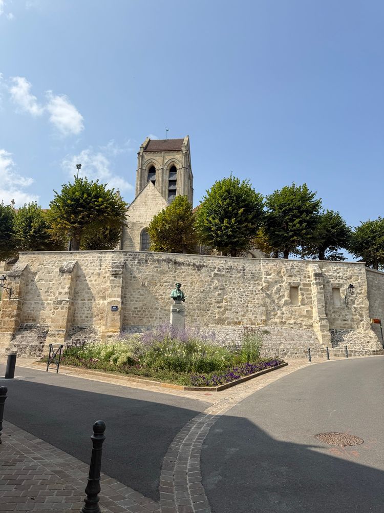 Vue de l’église d’Auvers-sur-Oise, un peu plus éloignée et on voit les deux routes qui partent l’une à droite et l’autre à gauche. Mais il y a un mur qui cache l’église