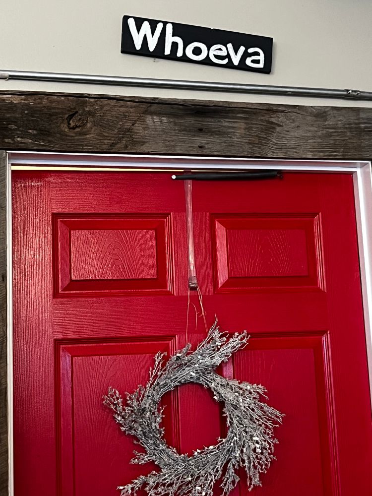 A red door with a sign saying “Whoeva”
