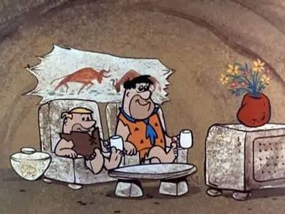 barney rubble and fred flintstone sitting next to each other in their own chairs, each holding their own mugs, watching tv together. the implication is that they're married or something idk