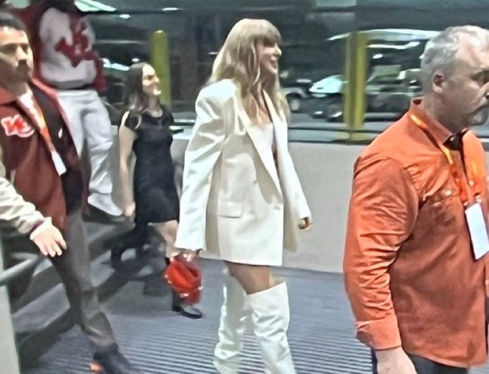A photo of Taylor Swift dressed in a white blazer and white thigh high boots arriving to the 2025 Super Bowl 