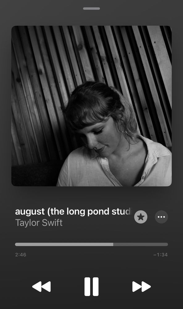 A from Apple Music showing the song “august (the long pond studio sessions)” by Taylor Swift. The album artwork features Taylor in a white button-down shirt, looking down with a gentle expression, seated in front of wooden studio paneling.