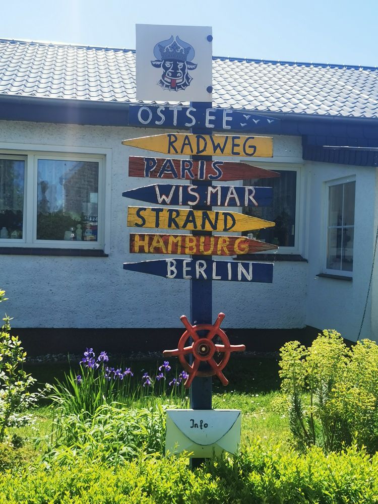 Ein selbst gebauter Wegweiser (in einem Vorgarten) auf dem Radweg zeigt folgende Richtungen an:
Ostsee, Paris, Wismar, Strand, Hamburg und Berlin.