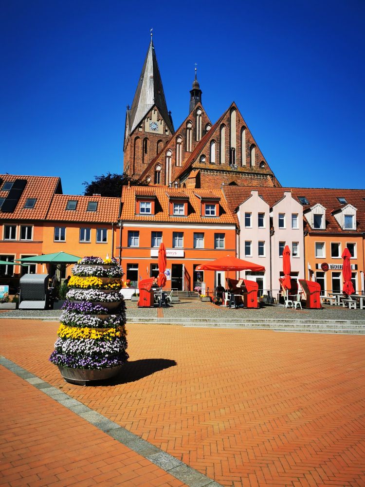 Marktplatz in Barth. Im Hintergrund ist die Kirche St. Marien zu sehen. Es herrscht sonniges Wetter mit blauem Himmel.