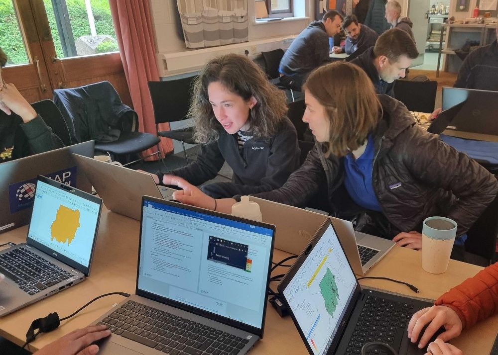 Two women discussing mapping at their laptops