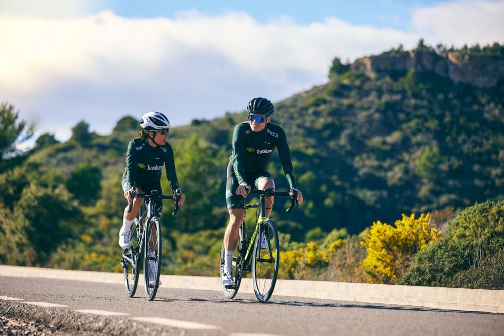 Two road cyclists in matching kit riding on a scenic mountain road, showcasing high-performance bikes ideal for UK riders -- find yours at MyNextBike.co.uk. 