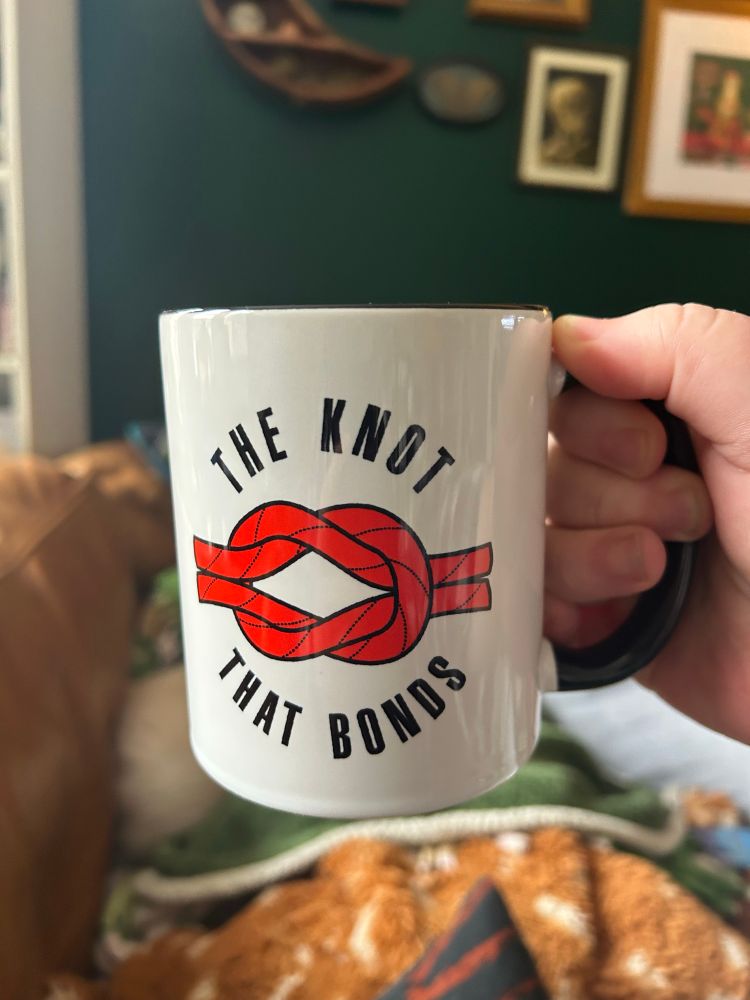 A mug full of hot chocolate that says “the knot that binds”