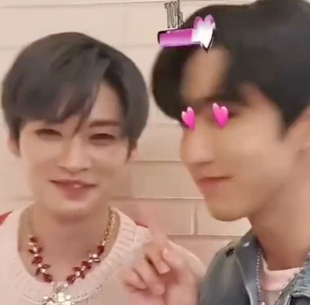 lee know and Han of stray kids posing in a picture together. Han has little pink heart eyes and Lee know is smiling at the camera, only one tooth showing